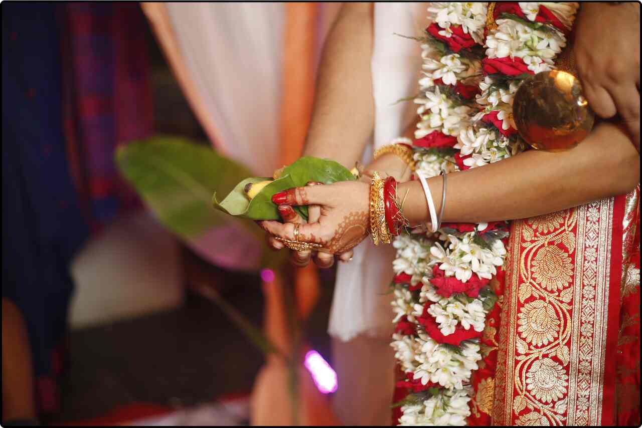 Bengali couple standing in front of the sacred fire, performing the homa ritual as part of their wedding ceremony.